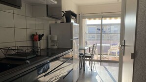 A modern kitchen with a coffee maker, a sink, and a dining area with a table and chairs.