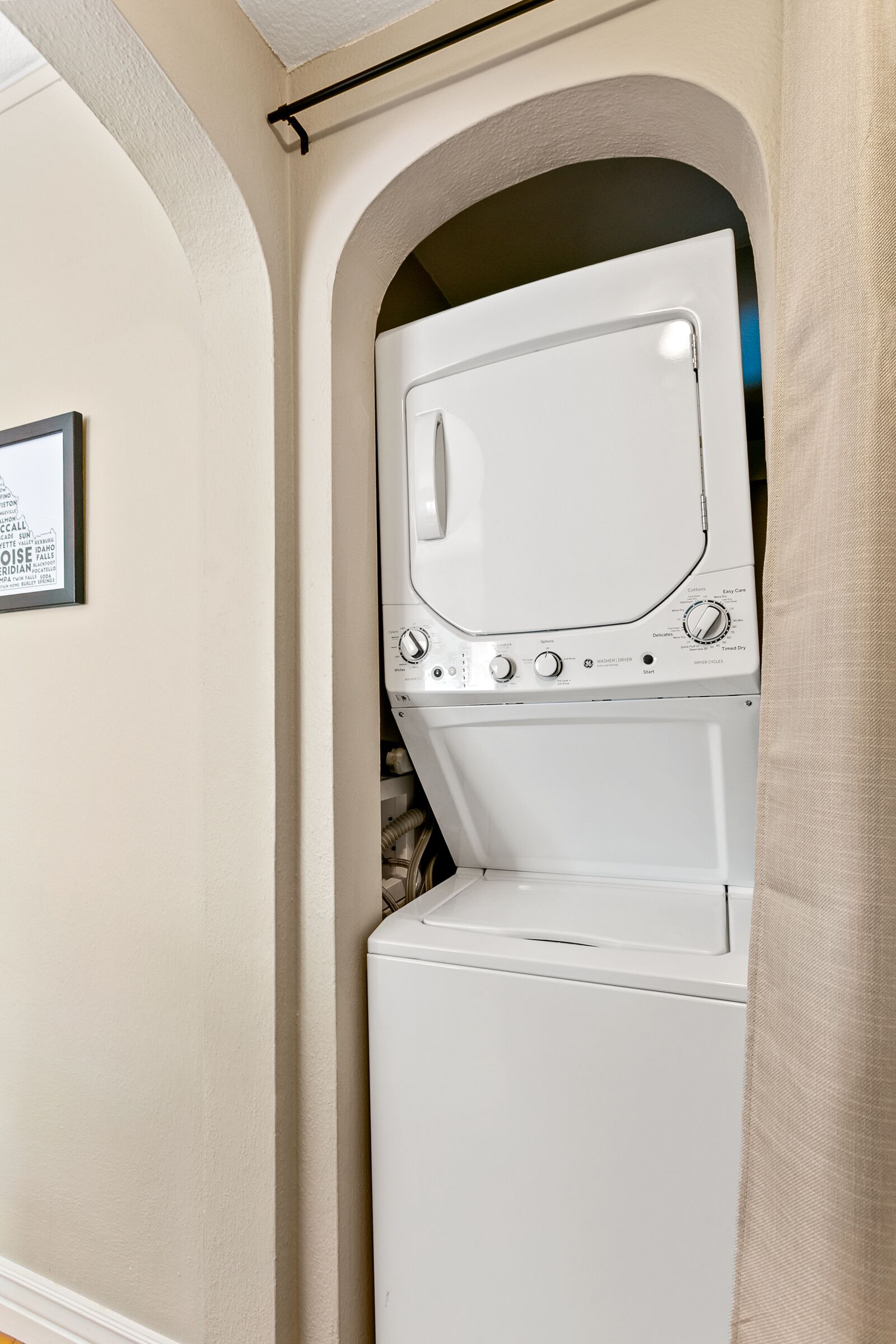 A laundry room with a washer and dryer, a framed sign on the wall, and an arched doorway.