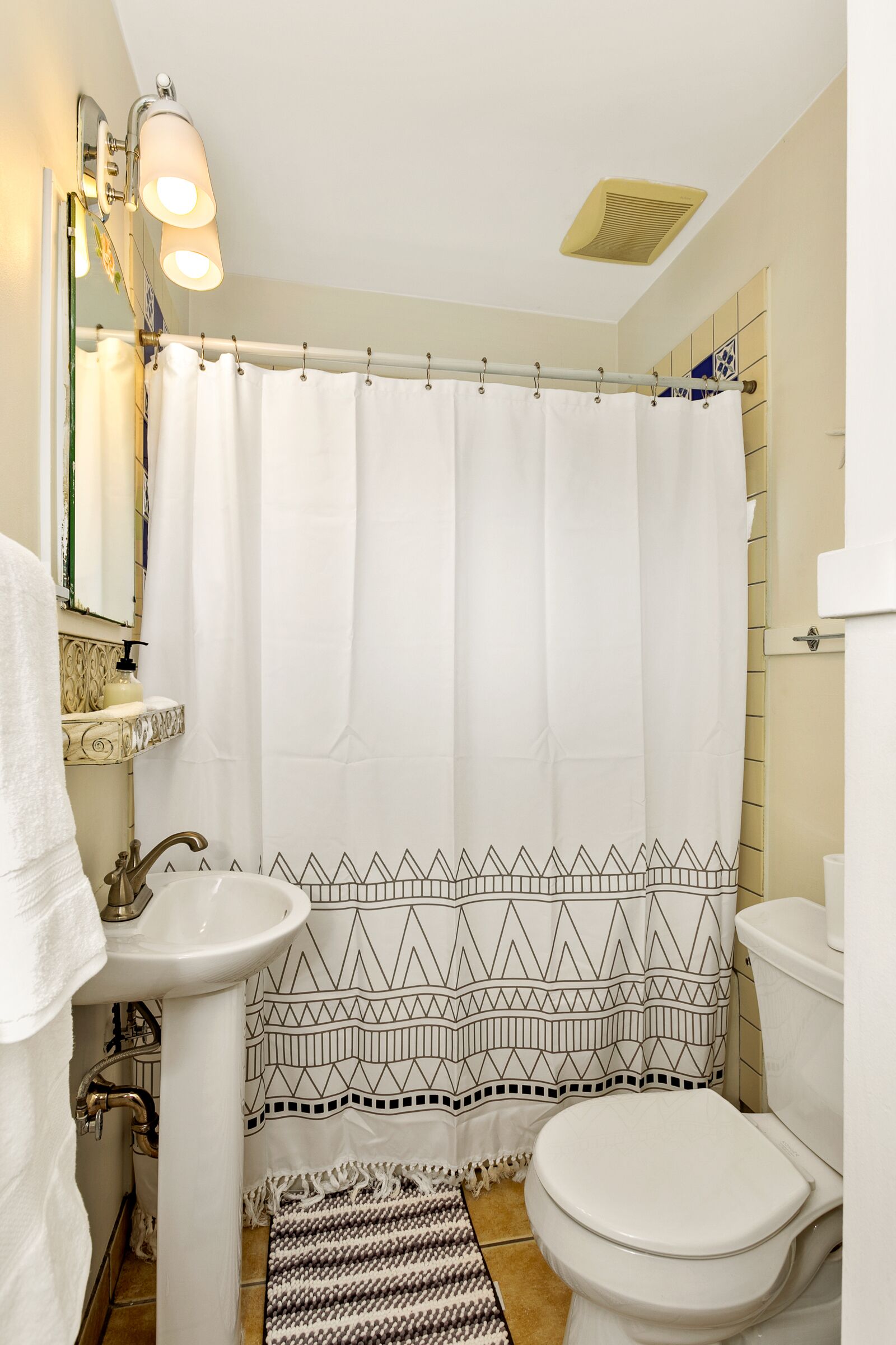 A bathroom with a white sink, toilet, and shower curtain.