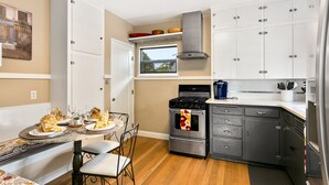 A modern kitchen with white cabinets, a stainless steel stove, and a window above the sink. - 1938 Cottage | Newly Remodeled | Coveted North End (Boise)