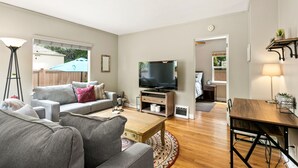 A modern living room with a grey sofa, wooden coffee table, and a flat-screen TV. - 1938 Cottage | Newly Remodeled | Coveted North End (Boise)