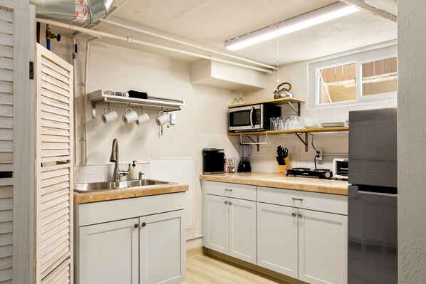 A modern kitchen with white cabinets, stainless steel appliances, and a wooden countertop. - CUTE Studio | Newly Remodeled | Blocks To Downtown (Boise)
