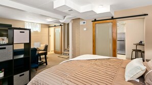 A bedroom with a bed, a desk, a chair, a wardrobe, and a small kitchenette area. - CUTE Studio | Newly Remodeled | Blocks To Downtown (Boise)