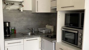A compact kitchen with a built-in microwave, oven, and sink. - Cozy Studio with Parking, AC, and WiFi in Balaruc-les-Bains (Balaruc-les-Bains)