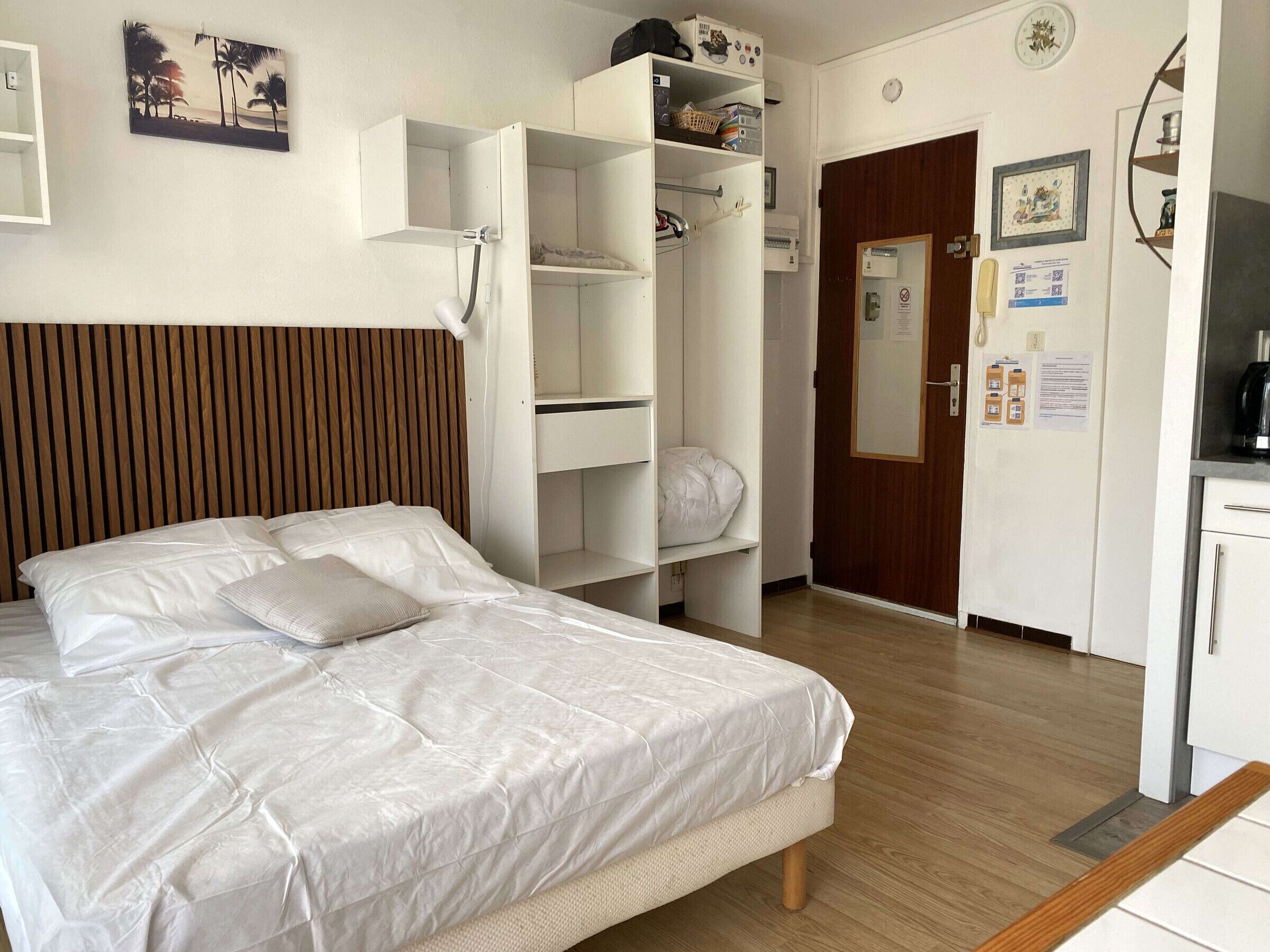 Una habitación de hotel con cama, armario, escritorio y espejo.