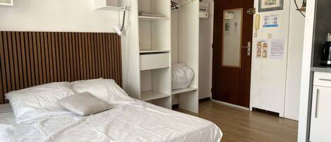 Una habitación de hotel con cama, armario, escritorio y espejo.
