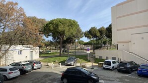 A parking area with multiple cars, a building with a beige facade, and a tree-lined street. - Cozy Studio with Parking, AC, and WiFi in Balaruc-les-Bains (Balaruc-les-Bains)