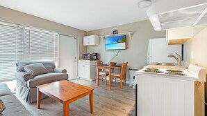 A compact living space with a kitchenette, a dining area, and a seating area with a sofa and a table.