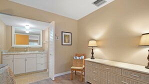 A kitchen with white cabinets, a wooden chair, and a side table with a lamp.