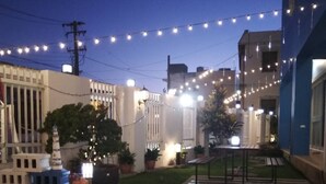 A courtyard with string lights, a small garden, and a building with a blue facade. - Bloom Boutique Resort (Hengchun)
