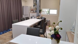 A modern dining area with a white table, grey chairs, and a decorative flower arrangement. - Bloom Boutique Resort (Hengchun)