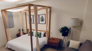 A bedroom with a canopy bed, a bedside table, a lamp, and a sofa. - Bloom Boutique Resort (Hengchun)