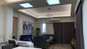 A modern office space with a white desk, two blue chairs, a chandelier, and a large window with curtains. - Bloom Boutique Resort (Hengchun)