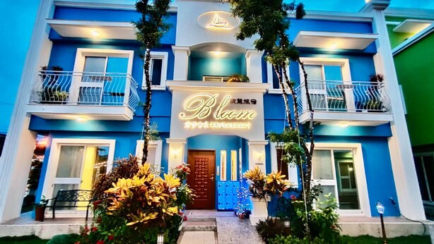 A hotel with a blue facade, a prominent sign reading "Bloom," and a well-maintained entrance with steps and potted plants. - Bloom Boutique Resort (Hengchun)