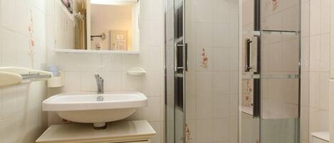 A bathroom with a sink, mirror, and shower.
