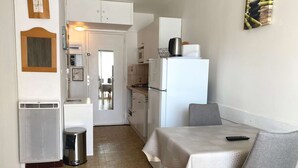 A compact kitchen with a refrigerator, microwave, and a small dining area with a table and chair. - Bright studio with air conditioning and wifi in Balaruc-les-Bains (Balaruc-les-Bains)