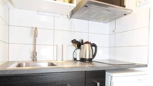 A kitchen with a stainless steel sink, a kettle, and a coffee maker on the countertop. - Cozy Studio with Garden, Near Thermes, WiFi, AC (Balaruc-les-Bains)