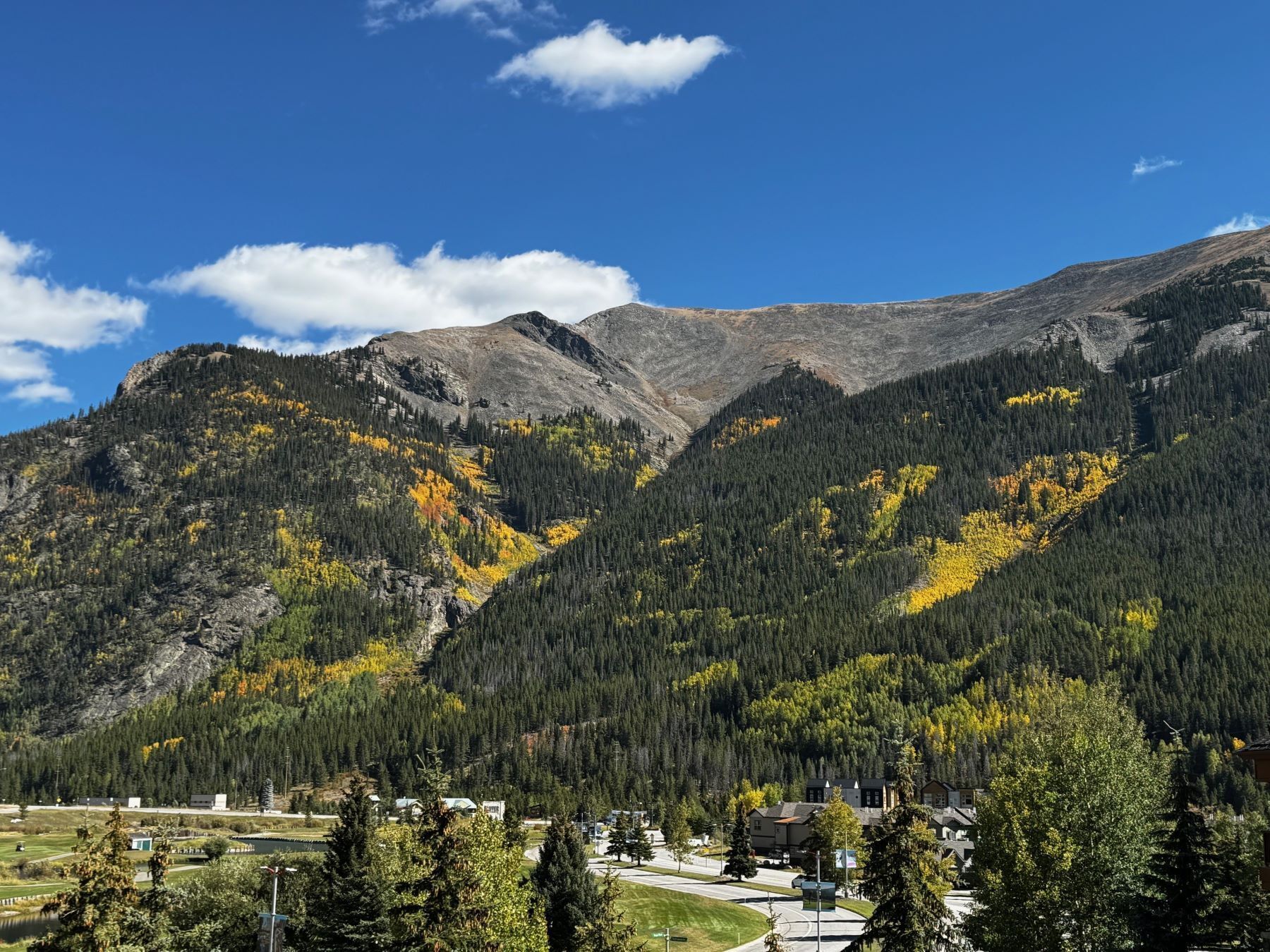 A mountainous landscape with a residential area in the foreground, featuring houses and a small body of water.