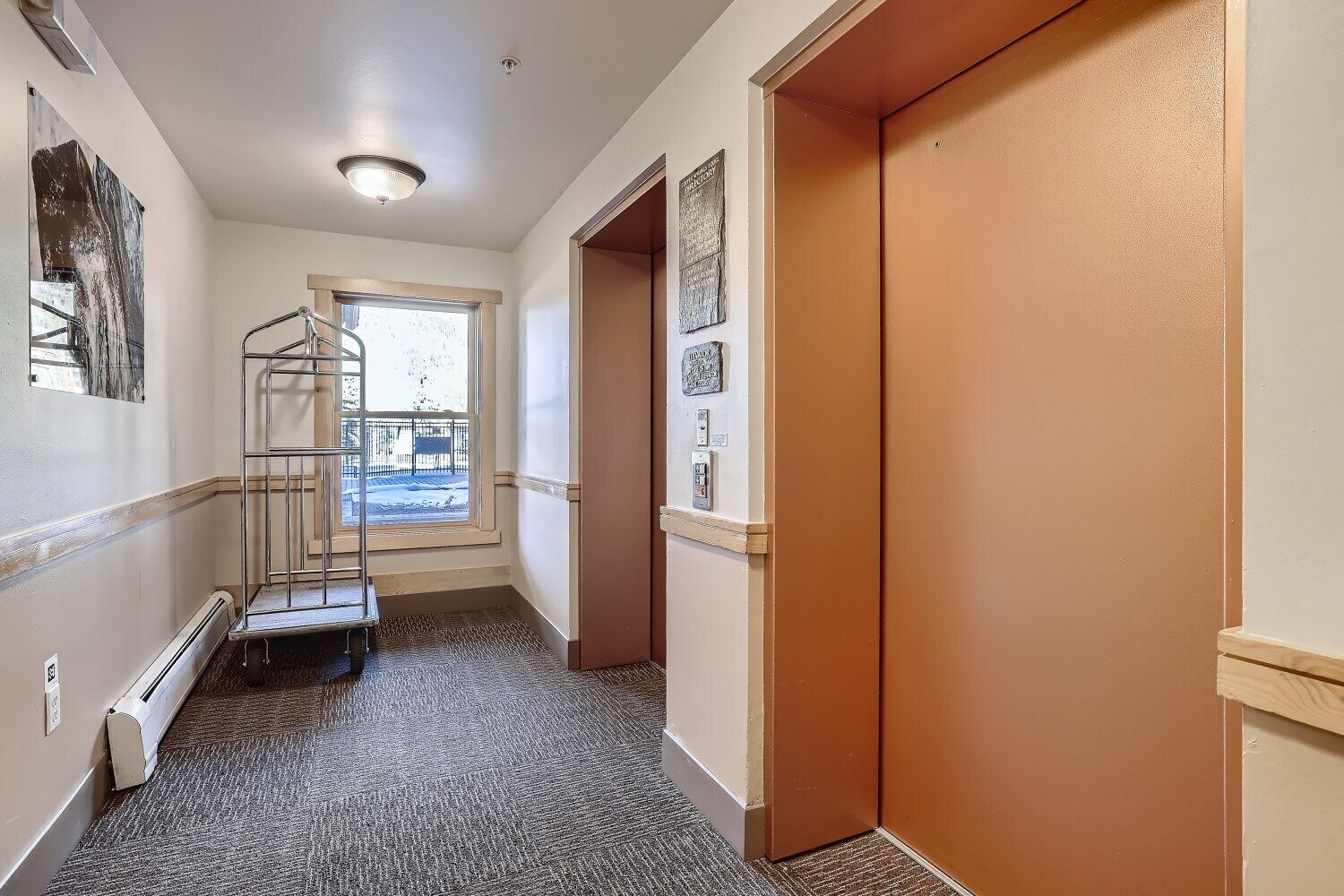 A hallway with a metal stairwell, a radiator, and a door with a light switch.