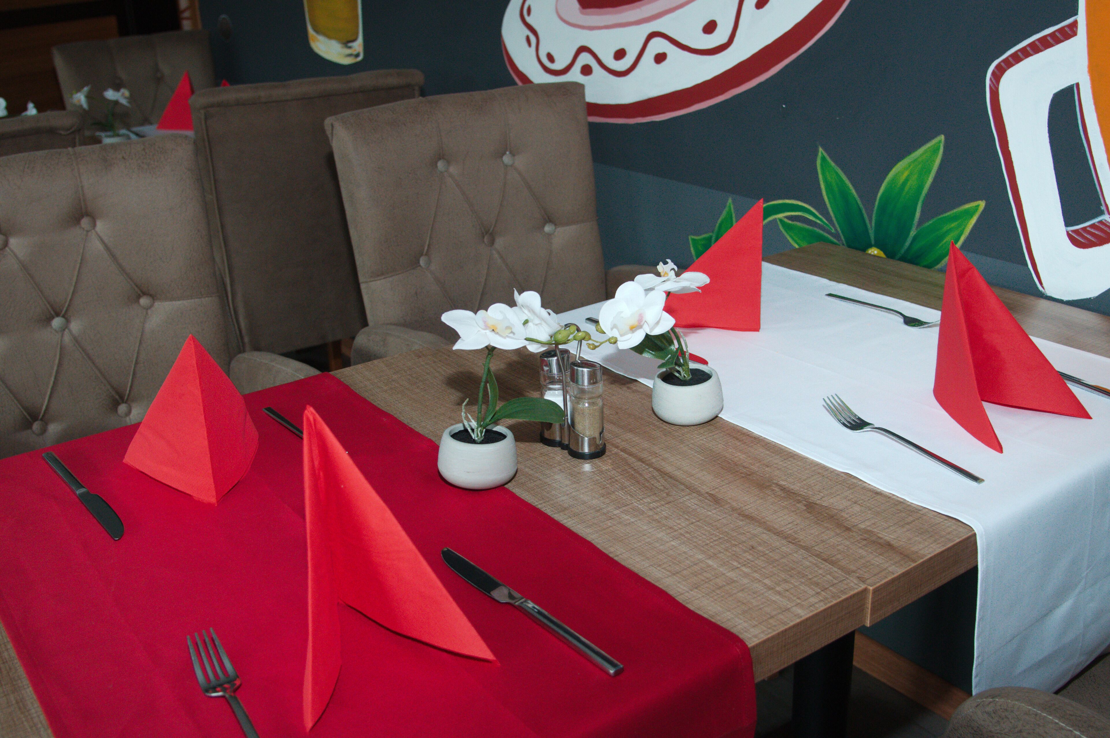 A dining table set with red napkins, white flowers, and a salt and pepper shaker.