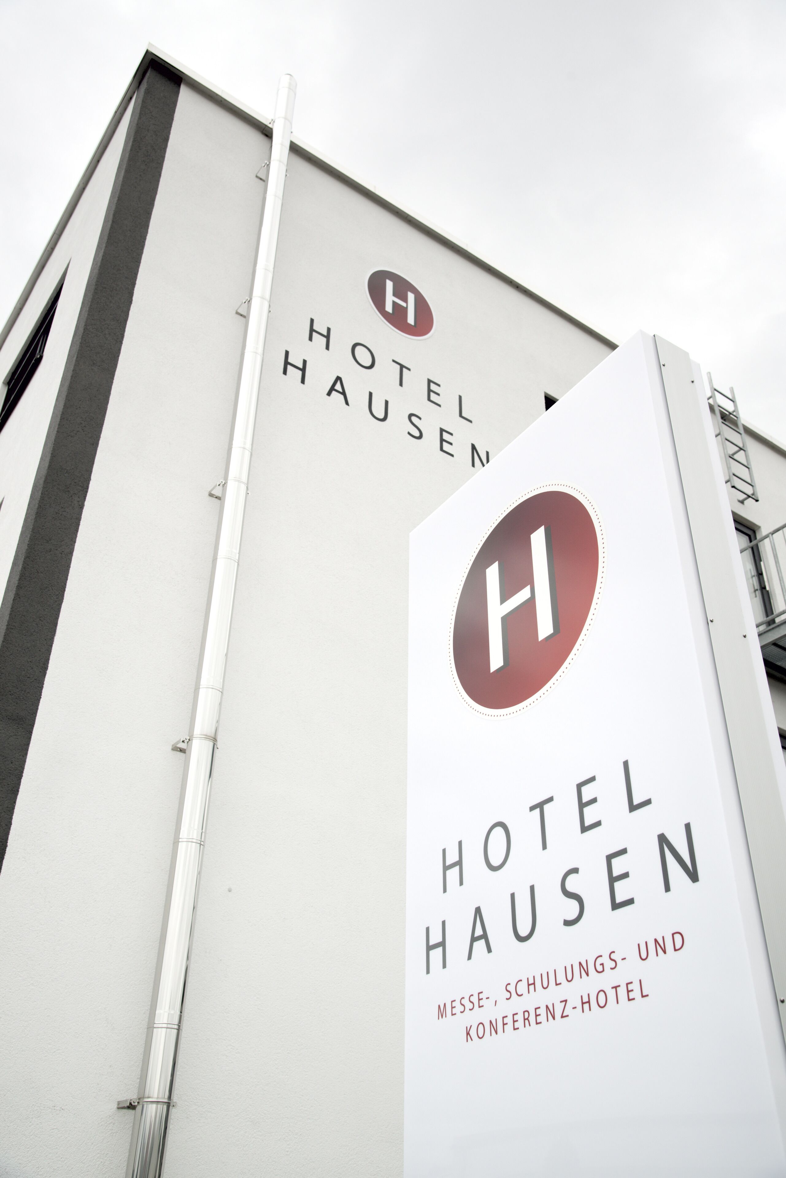 Un bâtiment sur lequel on peut lire l’inscription « HÔTEL HAUSEN » et « Hôtel pour congrès, formations et conférences ».