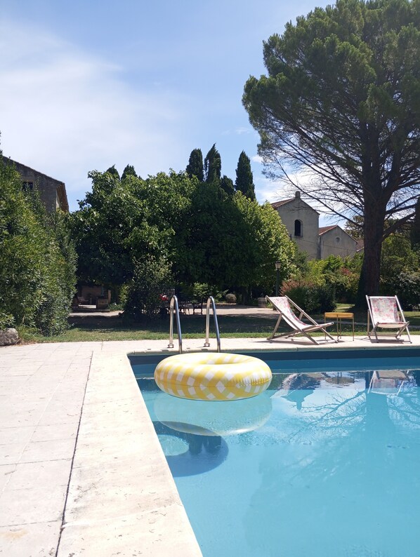 A swimming pool with a yellow inflatable ring, a lounge chair, and a tree in the background. - Rémy A Dit (St.-Rémy-de-Provence)