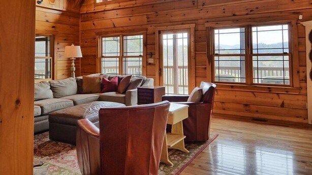 A spacious wooden cabin with a high ceiling, large windows, and a cozy seating area. - Experience luxury in this 6-bedroom cabin in Sugar Grove, NC, ideal for 12! (Sugar Grove)