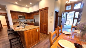 A modern kitchen with wooden cabinets, stainless steel appliances, and a granite countertop. - Mountain Thunder Townhome • Ski-In • Pools Hot Tubs • Walk to Main St (Breckenridge)