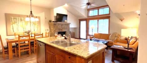 A spacious kitchen with a granite countertop, wooden cabinets, and a dining area with a table and chairs.