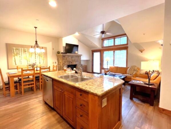 A spacious kitchen with a granite countertop, wooden cabinets, and a dining area with a table and chairs.