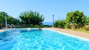 A swimming pool with clear blue water, surrounded by a wooden deck and lush greenery. - Villa Evelina | Private Pool (Adelianos Kampos)
