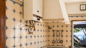 A kitchen with a sink, stove, and hanging utensils. - Charming windmill between nature and sea (Palmela)