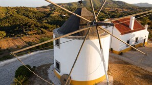 A windmill with a white and yellow base, a black roof, and a wooden structure with ropes.