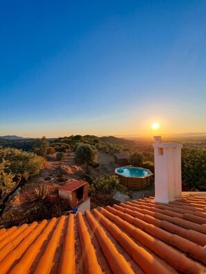 A rooftop terrace with a pool, a small cabin, and a view of the surrounding landscape.