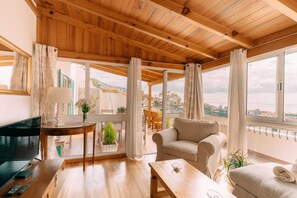 A cozy living room with a wooden ceiling, a sofa, a coffee table, and a TV. - Atlantic View Penthouse (Funchal)