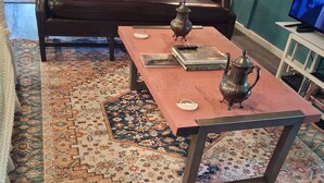 A living room with a brown leather sofa, a coffee table, and a patterned rug. - MONTHLY RENTAL, KING BED, HOT TUB, WIFI, KITCHEN, KENNARD TX. 159 HWY 7 #201 (Kennard)