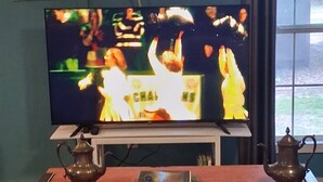 A television on a stand, a table with two teapots, and a patterned carpet. - MONTHLY RENTAL, KING BED, HOT TUB, WIFI, KITCHEN, KENNARD TX. 159 HWY 7 #201 (Kennard)