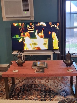 A television on a stand, a table with two teapots, and a patterned carpet. - MONTHLY RENTAL, KING BED, HOT TUB, WIFI, KITCHEN, KENNARD TX. 159 HWY 7 #201 (Kennard)