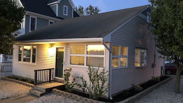 A single-story house with a front porch, a small deck, and a gravel driveway.
