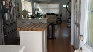Uma cozinha moderna com ilha central, geladeira e área de jantar com sofá e mesa.