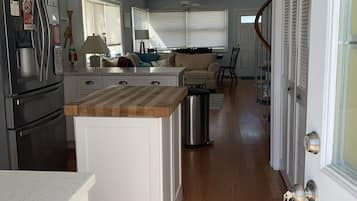 A modern kitchen with a central island, a refrigerator, and a dining area with a sofa and table.