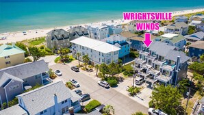 A residential area with beachfront properties, including a house with a balcony and a view of the beach. - Charming townhouse with beautiful ocean views and only steps to the beach! (Wrightsville Beach)