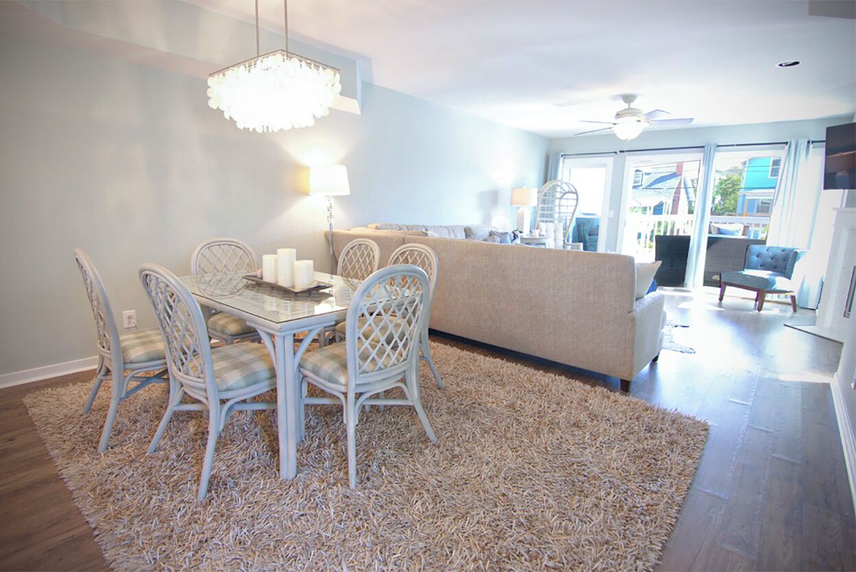 Un coin repas avec une table en verre, des chaises blanches et un tapis beige.