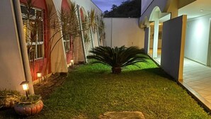 A well-lit courtyard with a lawn, a central plant, and a stone feature. - Hotel Teófilo Otoni (Teófilo Otoni)