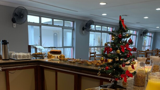 A breakfast buffet with various fruits, a Christmas tree, and a juice dispenser. - Hotel Teófilo Otoni (Teófilo Otoni)