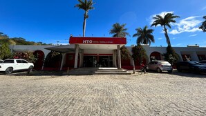 A hotel with a red and white facade, palm trees, and a cobblestone entrance. - Hotel Teófilo Otoni (Teófilo Otoni)
