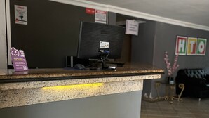 A reception desk with a sign reading "HTO" and a computer monitor on it. - Hotel Teófilo Otoni (Teófilo Otoni)