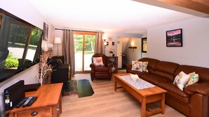 A living room with a brown leather sofa, a wooden coffee table, a brown armchair, a TV, and a fireplace. - Stay at One of the Most Convenient Locations in North Conway, NH! (North Conway)