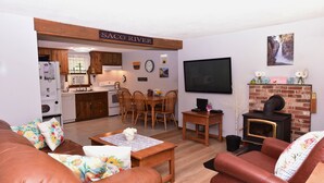A living room with a fireplace, a television, and a dining area with wooden furniture. - Stay at One of the Most Convenient Locations in North Conway, NH! (North Conway)