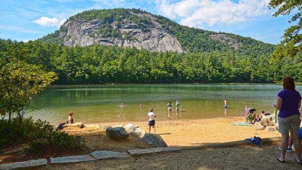 A lake with people swimming and standing on the shore, surrounded by a forested mountain. - Stay at One of the Most Convenient Locations in North Conway, NH! (North Conway)